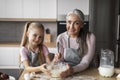 Cheerful pretty caucasian senior grandmother with small granddaughter make dough for baking Royalty Free Stock Photo