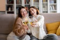 Cheerful pretty european millennial women in sweaters cheers glasses of wine, enjoy relax and free time