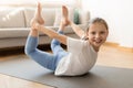 Cheerful pretty european teenage girl in sportswear doing pilates exercises for legs