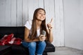 Cheerful pretty girl watching tv, sitting on sofa at home. Royalty Free Stock Photo
