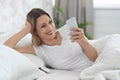 Cheerful pretty lady using cell phone in bed Royalty Free Stock Photo