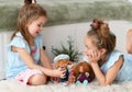 Cheerful pretty small girls sisters kids with long hair in same clorhing playing with toys dolls together