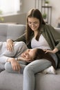 Cheerful pretty teenager daughter cuddling young mom lying on sofa