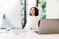 Cheerful pretty woman sitting at desk with hands behind head. Business lady imagines happy future with closed eyes. Relaxed girl Royalty Free Stock Photo