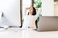 Cheerful pretty woman sitting at desk with hands behind head. Business lady imagines happy future with closed eyes. Relaxed girl Royalty Free Stock Photo