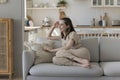 Cheerful pretty young adult girl sitting on cozy soft couch Royalty Free Stock Photo