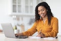 Cheerful pretty black lady working from home, taking notes Royalty Free Stock Photo