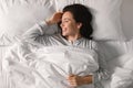 Cheerful pretty young european lady sleeping on white bed, waking up, enjoying good morning, vacation Royalty Free Stock Photo