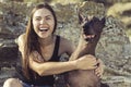 Cheerful pretty young girl sitting and hugging her dog xoloitzcuintli on the stoun beach at sunset Royalty Free Stock Photo