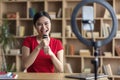 Cheerful pretty young japanese female superstar singing at microphone, shooting blog on smartphone