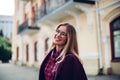 Cheerful pretty young lady holds his glasses her hands and smiles at his interlocutor.Girl wearing stylish burgundy coat and a shi Royalty Free Stock Photo