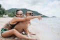 Cheerful asian young woman in eyeglases sitting and hugging her dog on the beach Royalty Free Stock Photo