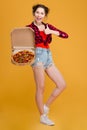 Cheerful pretty young woman holding pizza and showing thumbs up Royalty Free Stock Photo