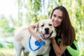 Cheerful pretty young woman sitting and hugging her dog at river bank Royalty Free Stock Photo