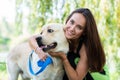 Cheerful pretty young woman sitting and hugging her dog at river bank Royalty Free Stock Photo