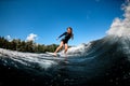 Cheerful pretty young woman in swimsuit rides down the wave on surfboard Royalty Free Stock Photo