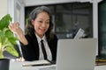 Cheerful Asian aged businesswoman having an online meeting, video conference with her team Royalty Free Stock Photo