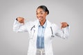 Cheerful professional young black doctor point fingers down at copy space, recommends ad and offer