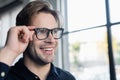 Cheerful programmer in eyeglasses looking away