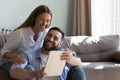 Cheerful proud husband showing gadget to happy wife at home