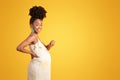 Cheerful proud millennial african american lady pointing finger at big belly