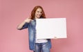 Red-haired girl holding blank advertising board and pointing on it Royalty Free Stock Photo