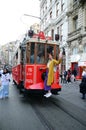 Cheerful red-haired girl rides on the steps of a moving red historical tram in Istanbul