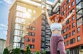 Cheerful red-haired woman raised her hands, rejoicing on the background of a new modern house Royalty Free Stock Photo