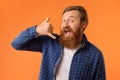 Cheerful redhaired bearded man gesturing Call Me on orange background