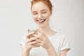 Cheerful redhead girl smiling looking at phone screen.