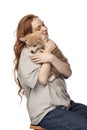 Cheerful redhead young girl with long curly hair holding cute little puppy of corgi dog isolated on white background