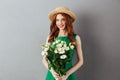 Cheerful redhead young woman holding flowers.