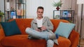 Cheerful young man sitting on sofa, using mobile phone share messages on social media application Royalty Free Stock Photo