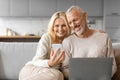 Cheerful retired couple using gadgets while relaxing together at home Royalty Free Stock Photo