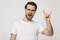 Millennial man in glasses showing rock and roll hand gesture