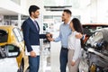 Cheerful sales associate giving arabic couple key from car Royalty Free Stock Photo