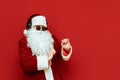 Cheerful Santa Claus in sunglasses dancing on a red background, listening to music in headphones and having fun at a party. Santa Royalty Free Stock Photo