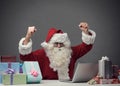 Cheerful Santa connecting with his laptop