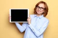 Satisfied smiling businesswoman in blue shirt showing black empty screen with copy space on digital tablet, beige background Royalty Free Stock Photo