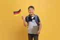 Cheerful school boy showing flag of Germany, yellow background Royalty Free Stock Photo