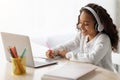 Cheerful school girl having online lesson, using laptop at home Royalty Free Stock Photo