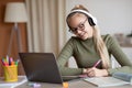 Cheerful school girl having online lesson, using laptop at home Royalty Free Stock Photo