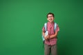 Cheerful schoolboy with glasses, holding book and backpack on green background Royalty Free Stock Photo