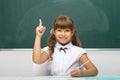 Cheerful schoolgirl pointing up her finger. Photo session in the studio