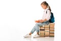 cheerful schoolkid sitting on books and reading on white.