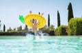 Cheerful Screaming boy in yellow pineapple inflatable ring having fun and jumping into swimming pool. Merry childhood or summer Royalty Free Stock Photo