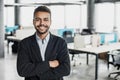 Cheerful self confident man with crossed hands portrait. Handsome young businessman with folded arms in the office