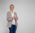 Cheerful senior businesswoman using mobile phone and looking at camera on isolated white background Royalty Free Stock Photo