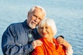 Cheerful senior citizens woman and man are standing and hugging on the lake, against the background of the bridge Royalty Free Stock Photo