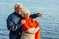 Cheerful senior citizens woman and man are standing and hugging on the lake, against the background of the bridge Royalty Free Stock Photo